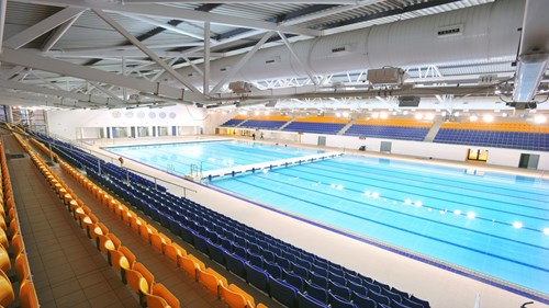 Competition pool within Tollcross International Swimming Centre. There are rows of seats surrounding the pool