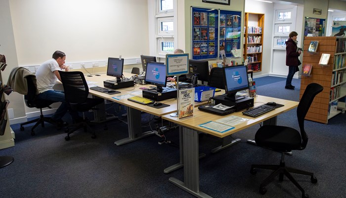 A large rectangular table with black PC's around it. 