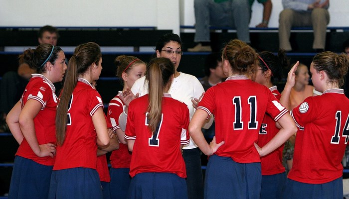 A coach talks to a group of young women, who are in a Volleyball team