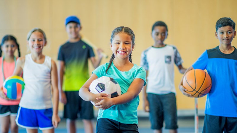 a group of boys and girls holding different sporting equipment