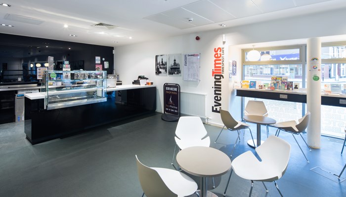 Cafe area with a black counter and white tables and chairs.