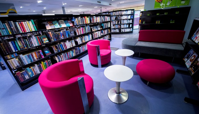 Black bookshelves with pink circular soft chairs on a purple carpet