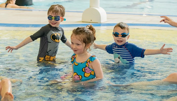 Three children playing in the water of a swimming pool