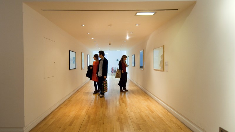 Visitors look at pictures on a gallery wall at GoMA