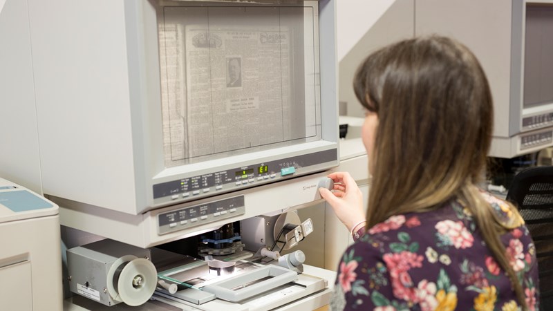 Person using a newspaper reader at the Mitchell