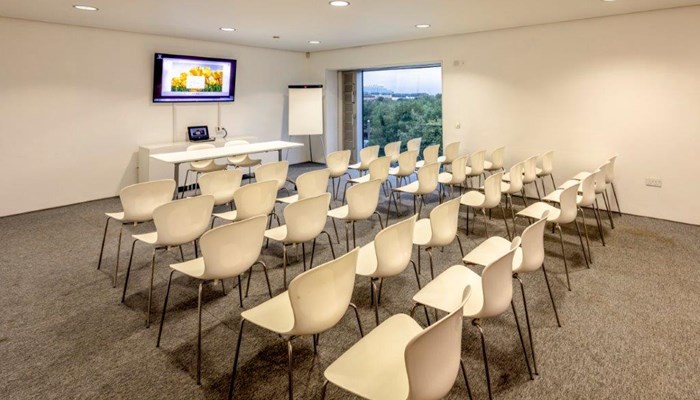 rows of white chairs lined up and facing towards a board ready for a presentation