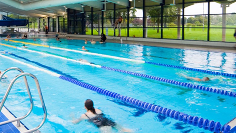 Swimming pool with lanes and large blue slide in background 