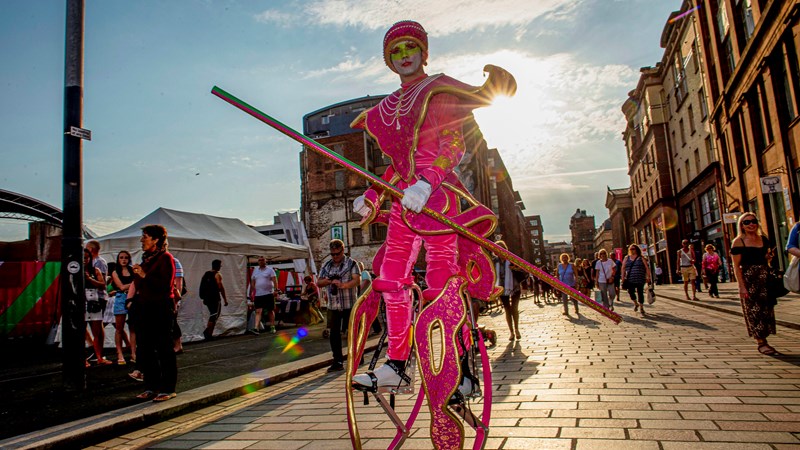 Carnival street person dressed in pink and on stilts