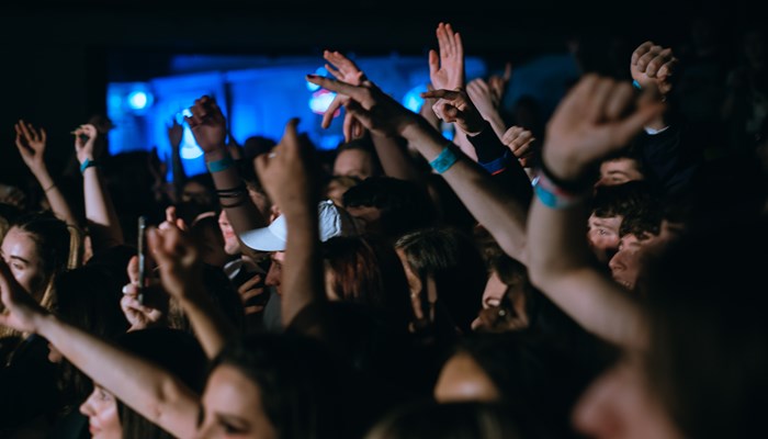 A crowd in a darkened venues, arms raised in celebration