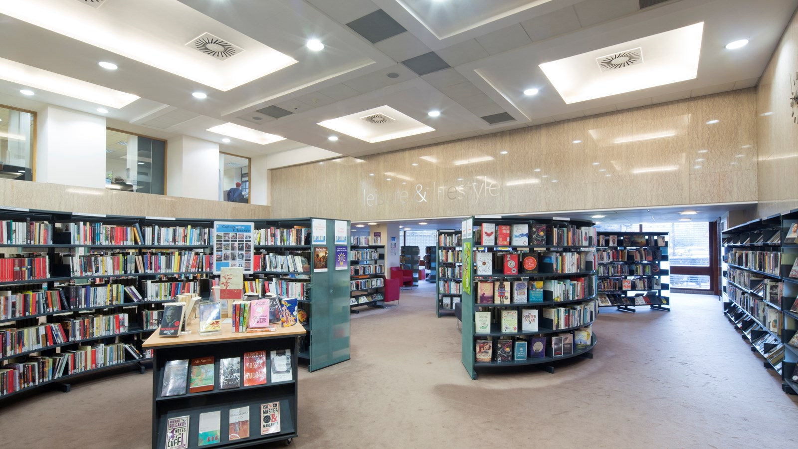 Lots of books in many colours on shelves and displayes in a library.